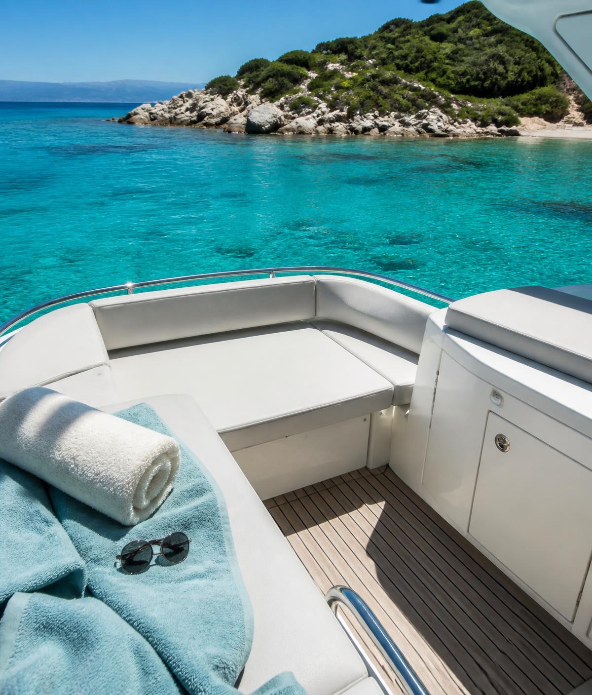 Boat deck with cushioned seats anchored on clear turquoise water